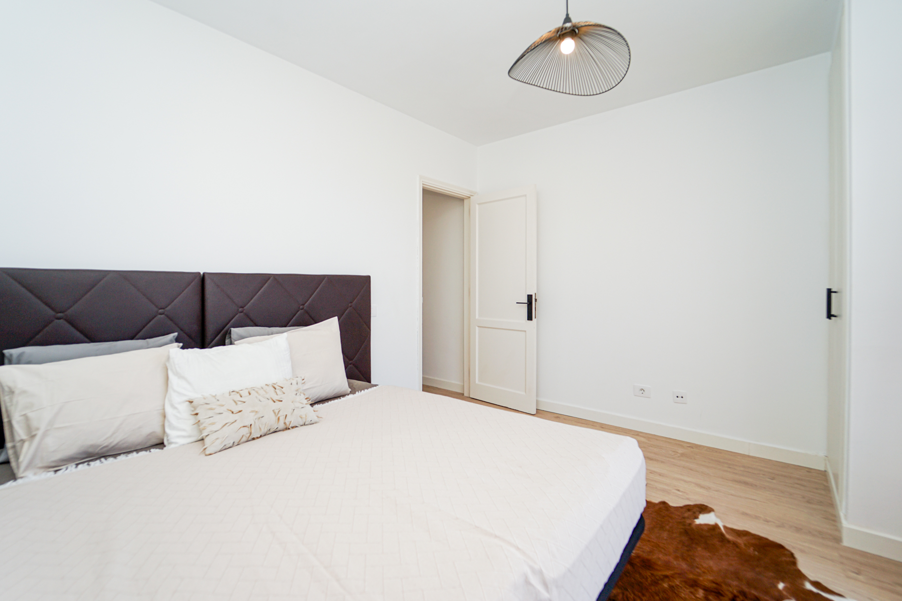 Second bedroom with quilted headboard and minimalist coastal design