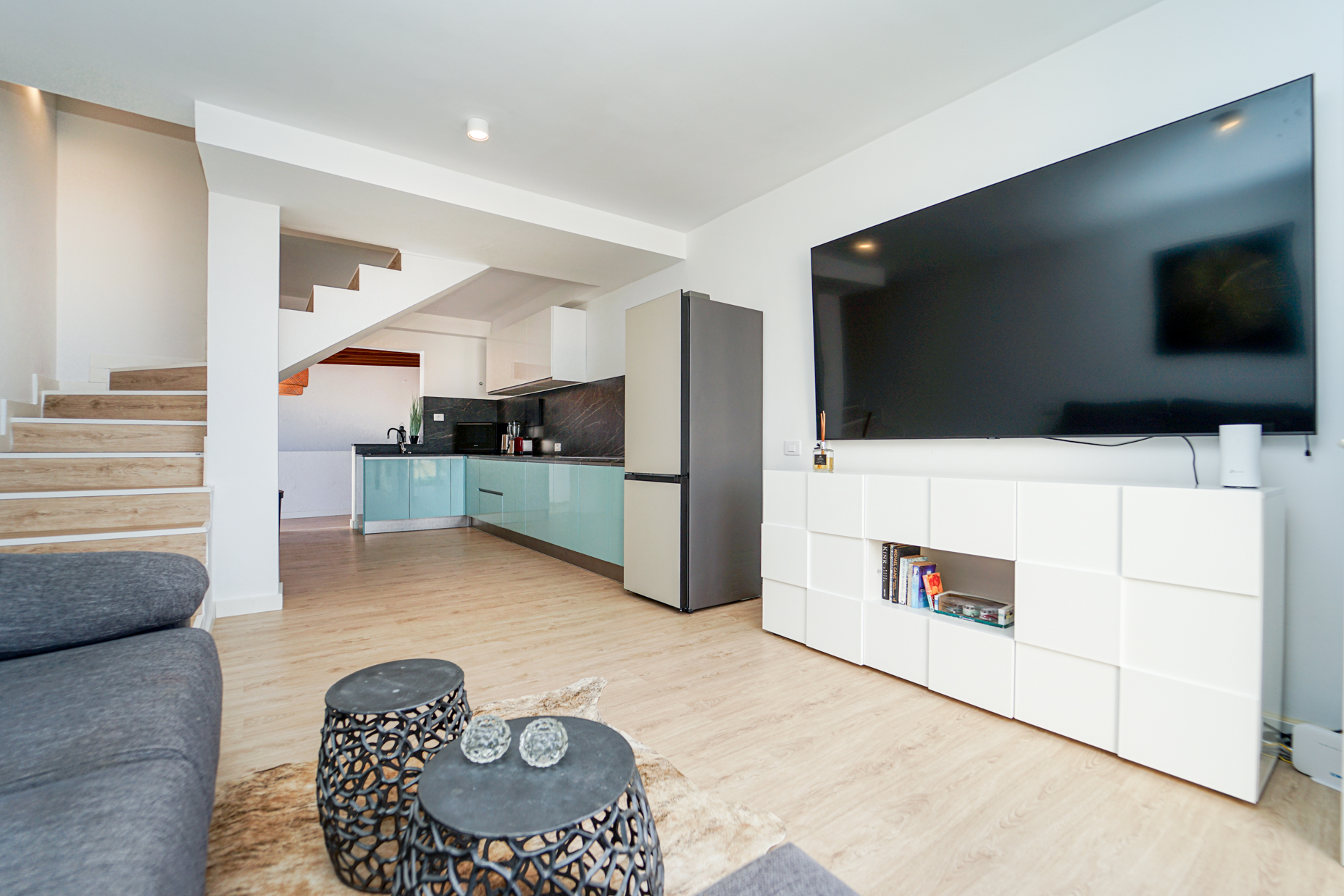 Open plan living area with kitchen, stairs, and modern coastal design
