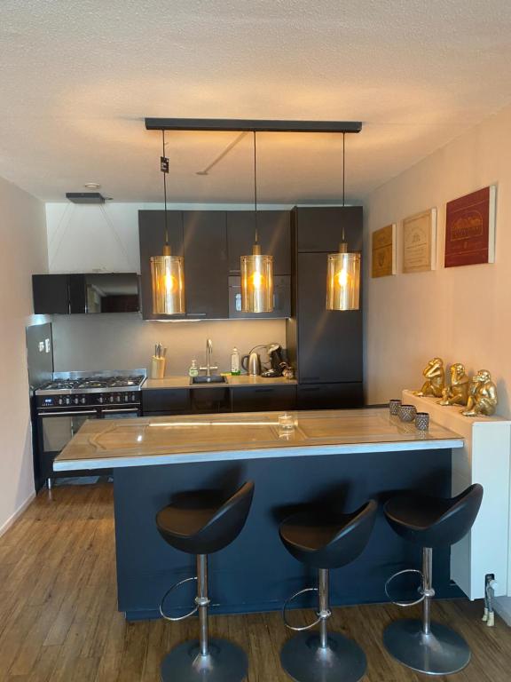 Modern kitchen with blue cabinets, wood countertops and designer pendant lighting