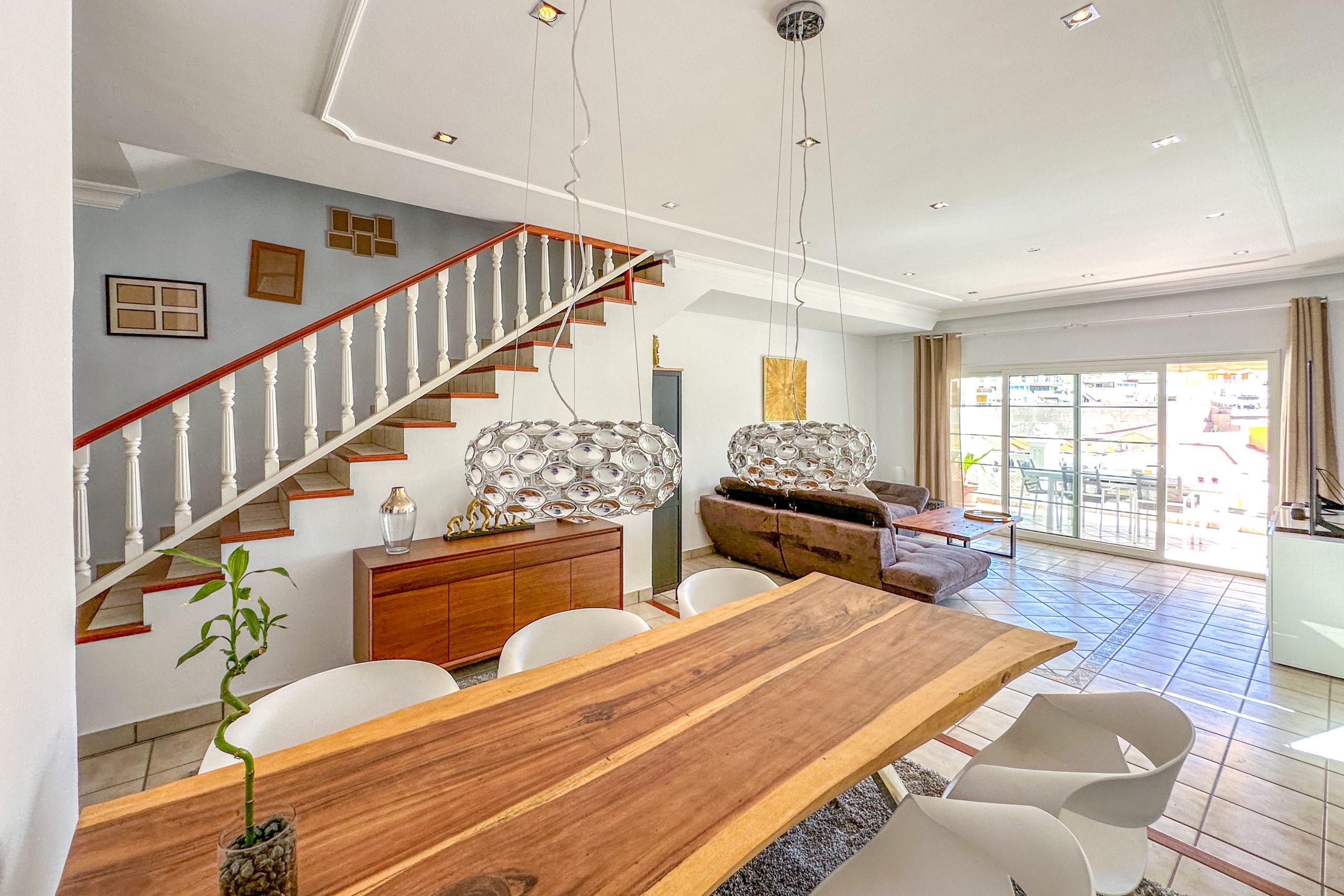 Modern interior living and dining area with wooden staircase